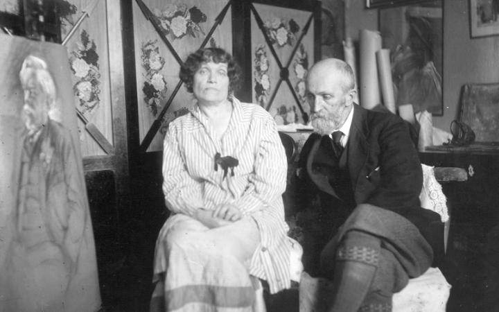 Дмитрий Николаевич и Ольга Людвиговна Кардовские сидят на стульях в комнате, сзади ширма, рисунки